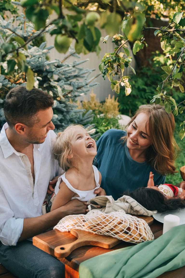 Family enjoying quality time outdoors under a tree, capturing smiles and joyful moments.
